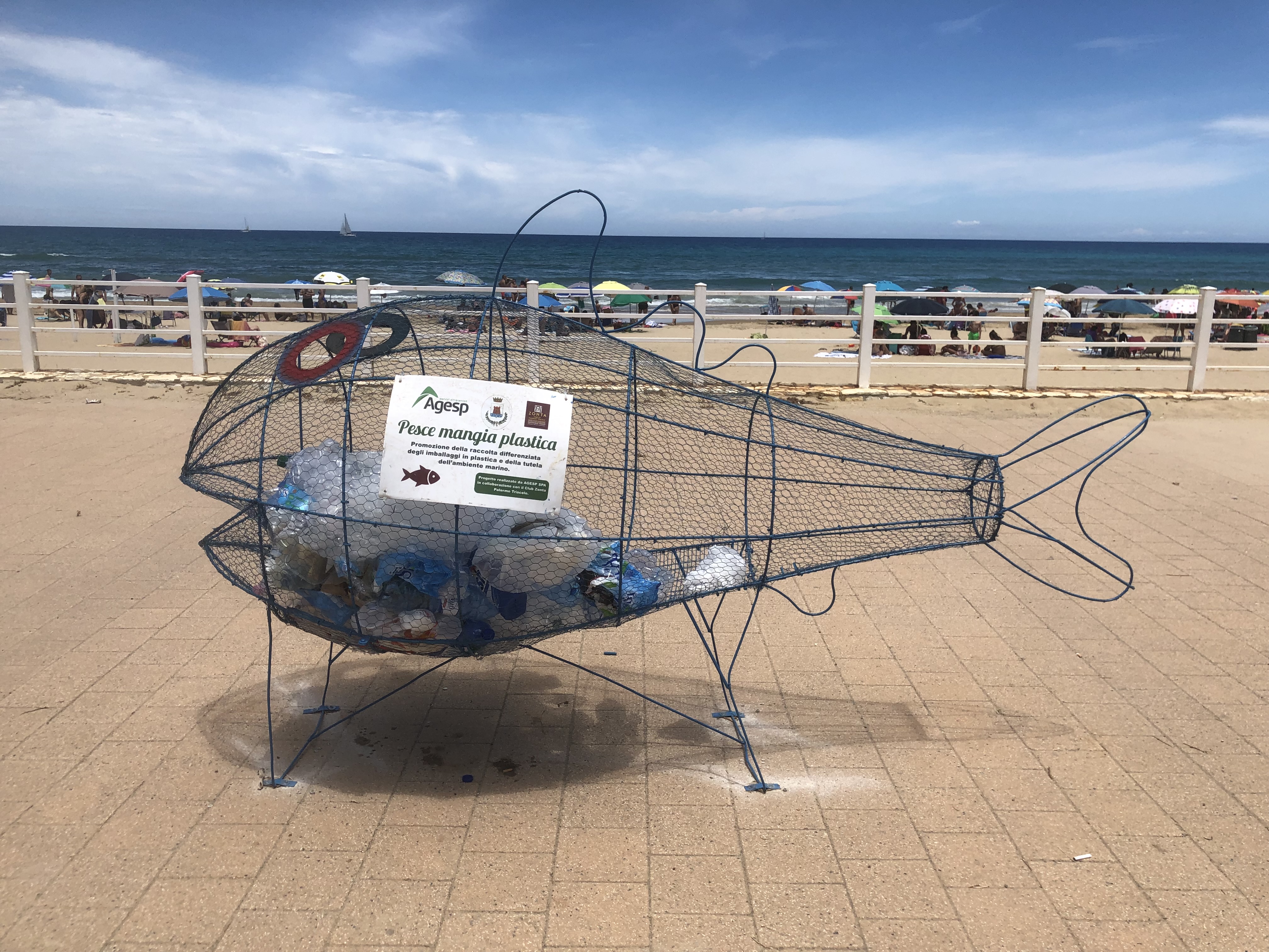 Plastic fish sculpture filled with plastic waste on a beach promenade